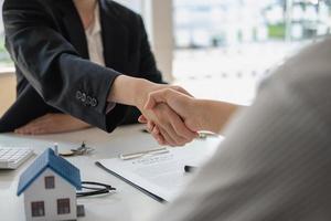 garanties, hypotheken, ondertekening, contract, overeenkomstconcept, makelaars schudden klanten de hand na ondertekening van het contract en feliciteren hen na het bereiken van een overeenkomst. foto