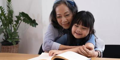 gelukkige Aziatische familie grootmoeder lezen aan kleindochter kinderboek thuis foto