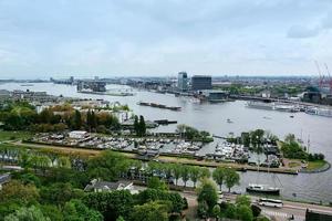 Amsterdam, Nederland - 28 april 2019 uitzicht op de stad naar het centrale deel van de stad, de veerboot en het kanaal van bovenaf in bewolkte typisch Nederlandse dag. foto