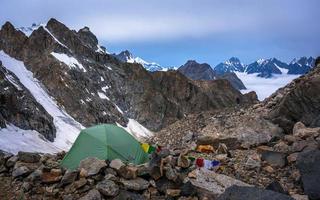 eenzame bergbeklimmers kamperen in zeer hoge besneeuwde bergen naast de gletsjer. foto