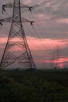 elektrische toren in het veld bij zonsopgang foto