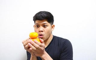 aantrekkelijke aziatische man die sinaasappels eet. geïsoleerd op witte achtergrond foto