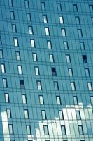 blauwe lucht en wolken weerspiegeld op de moderne gespiegelde gevel van het gebouw. foto