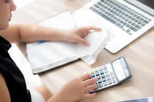 close-up hand vrouw die uitgaven huishouden berekent en notitieboekje op bureau schrijft, meisje dat rekening en stress en notitie controleert, vrouwelijke zorgschuld en belasting, financiën en bedrijfsconcept. foto