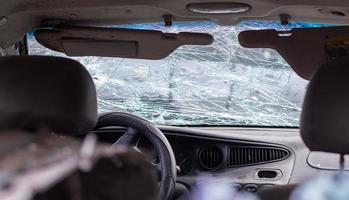 beschadigde autoruit na een ongeval. gebroken voorruit als gevolg van een ongeval, binnenaanzicht. details van het interieur van de cabine, zicht vanuit de cabine. veilige beweging. gebroken voorruit. glas barst en beschadigingen. foto