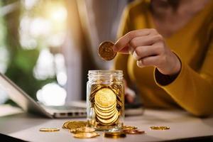 geld besparen met de hand die zakenvrouw houdt die munten in glas steekt foto