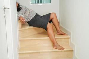 Aziatische dame vrouw verwondingen door vallen op gladde oppervlakken trappen thuis. foto