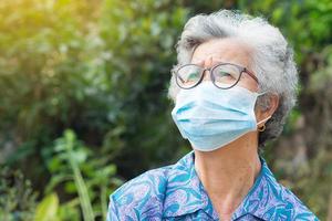 oudere vrouw die een masker draagt terwijl ze in een tuin staat foto