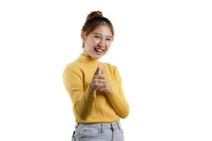 portret van een mooie aziatische vrouw in een geel shirt dat staat en wijst. portret concept gebruikt voor reclame en bewegwijzering, geïsoleerd over de lege achtergrond, kopieer ruimte. foto