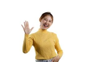 portret van een mooie aziatische vrouw in een geel shirt die met haar handen in vreugde staat. portret concept gebruikt voor reclame en bewegwijzering, geïsoleerd over de lege achtergrond, kopieer ruimte. foto