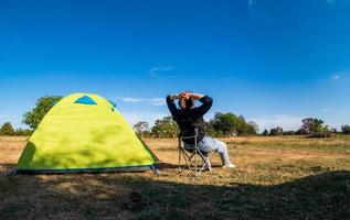 Aziatische vrouwelijke toeristen zitten gelukkig vrij met groene tent voor reiziger zit op breed veld, met uitzicht op de avondtijd van privégebied thailand voor kampeervakantie tijdens lange vakantie om te reizen. foto