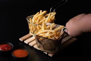 Franse frietjes in een mand op een zwarte achtergrond foto