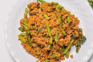 roergebakken chilipasta met gemalen varkensvlees in een wit bord thais zuiders gekruid roergebakken thais eten foto