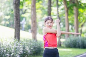 sportvrouw die buitenshuis opwarmt, fitnessvrouw die rekoefeningen doet die haar armen strekken - triceps en schouders strekken foto