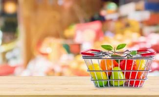 winkelmandje met fruit op houten tafel over supermarkt supermarkt wazige achtergrond foto