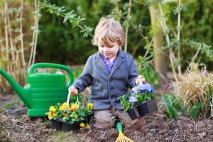 kleine jongen tuinieren en bloemen planten in de tuin