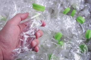 man hand houdt plastic flessen vast, recycle en bescherm de wereld tegen het broeikaseffect foto