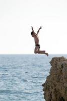 man springen van een hoge rots in de zee