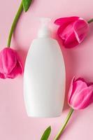 spa huidverzorgingsproducten op een roze achtergrond. natuurlijke cosmetica en rode tulpen. foto