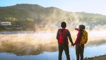 Aziatische vrouw en Aziatische man die backpacken in de buurt van het meer, ze glimlachte, gelukkig en genoot van de natuurlijke schoonheid van de mist. foto