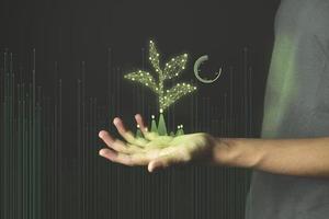 eco-technologiehand met gloeiende lage poly groene spruit op donkerblauwe achtergrond foto