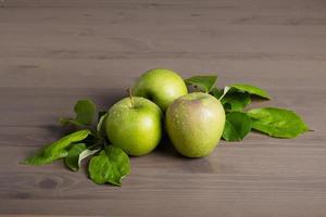verse rijpe groene appels en appelboombladeren op een houten ondergrond foto