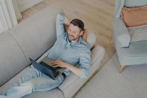 jonge bedrijfsmedewerker in vrijetijdskleding ontspannen na succesvolle online presentatie foto