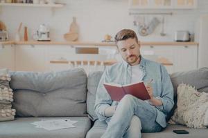 jonge man schrijft in notitieboek terwijl hij op de bank zit foto