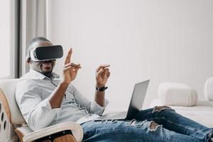 Afro-Amerikaanse man in vr-bril werkt thuis. ontspannen zakenman klikt op virtuele knoppen. foto