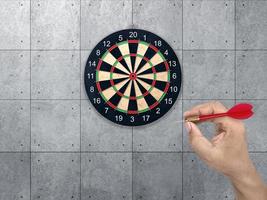 hand met darts pijl. doel voor darts. betonnen muur achtergrond. concept marketing doel foto