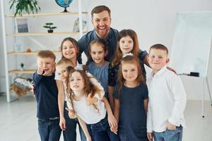 samen staan. groep kinderen studenten in de klas op school met leraar foto