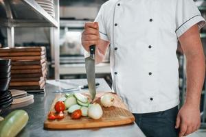 man maakt salade. professionele chef-kok die voedsel in de keuken bereidt foto