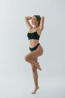 staande in zwarte lingerie. vrouw in ondergoed met slank lichaamstype poseert in de studio foto
