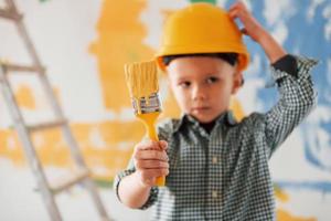 blauwe en gele kleuren erachter. conceptie van Oekraïne en vrede. kleine jongen die muren in de huiskamer schildert foto