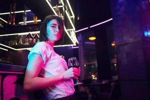 vrouw met bruin haar die in de nachtclub staat en een drankje vasthoudt foto