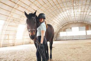overdag. een jonge vrouw in jockeykleding bereidt zich voor op een ritje met een paard op een stal foto