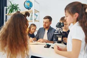 werken met de microscoop. groep kinderen studenten in de klas op school met leraar foto