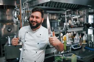 met scherpe messen. professionele chef-kok die voedsel in de keuken bereidt foto