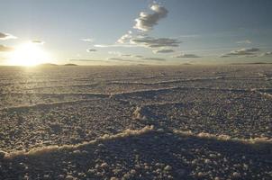 prachtige patronen op het oppervlak van de zoutvlakten van salar de uyuni, bolivia, tijdens zonsondergang foto