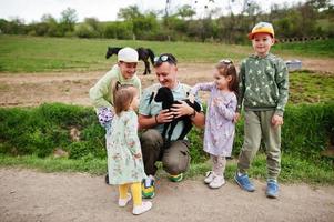 vader met vier kinderen op een eco-boerderij met dieren houdt een schaapslam in de hand. foto