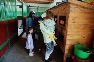 kinderen op een dierenboerderij kijken naar kooien met konijnen. foto