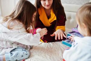 moeder en dochters doen manicures op het bed in de slaapkamer. foto