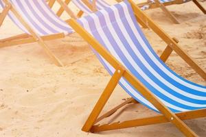 blauw en wit gestreepte ligstoelen staande op zand op een strand foto