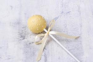 een gele cakepop op een gestructureerde achtergrond foto