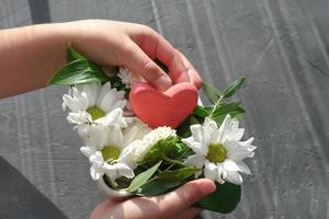 meisjeshanden met rood hart en witte bloemen foto