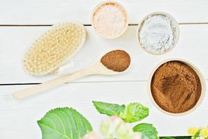 zelfgemaakte exfoliërende scrub ingrediënten. gemalen koffie, Himalaya roze zout, kleipoeder en lichaamsborstel op houten tafel. lente lichaamsverzorging, reiniging en vernieuwing voor de huid. bovenaanzicht. foto