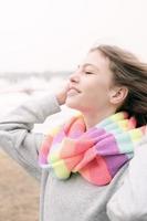 openluchtportret van een tienermeisje dat gestreepte sjaal draagt en geniet van warme wind. glimlachend gelukkig vrolijk meisje op een rivieroever foto