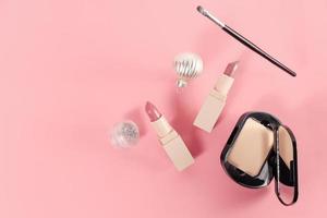 set met make-up producten en kerst decor op roze achtergrond. foto