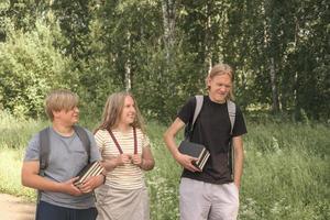 portret van een groep tieners van verschillende lengte met schooltassen en boeken die naar school komen, terug naar school concept. lange tienerjongen lacht en andere vrienden kijken naar hem foto