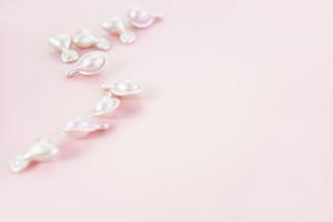 roze cosmetische capsules op roze achtergrond. serum of crème foto